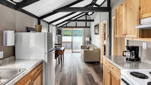 Cocina moderna con comedor, armarios de madera, refrigerador blanco y cafetera.