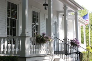 A white building with a porch, columns, and a flag.