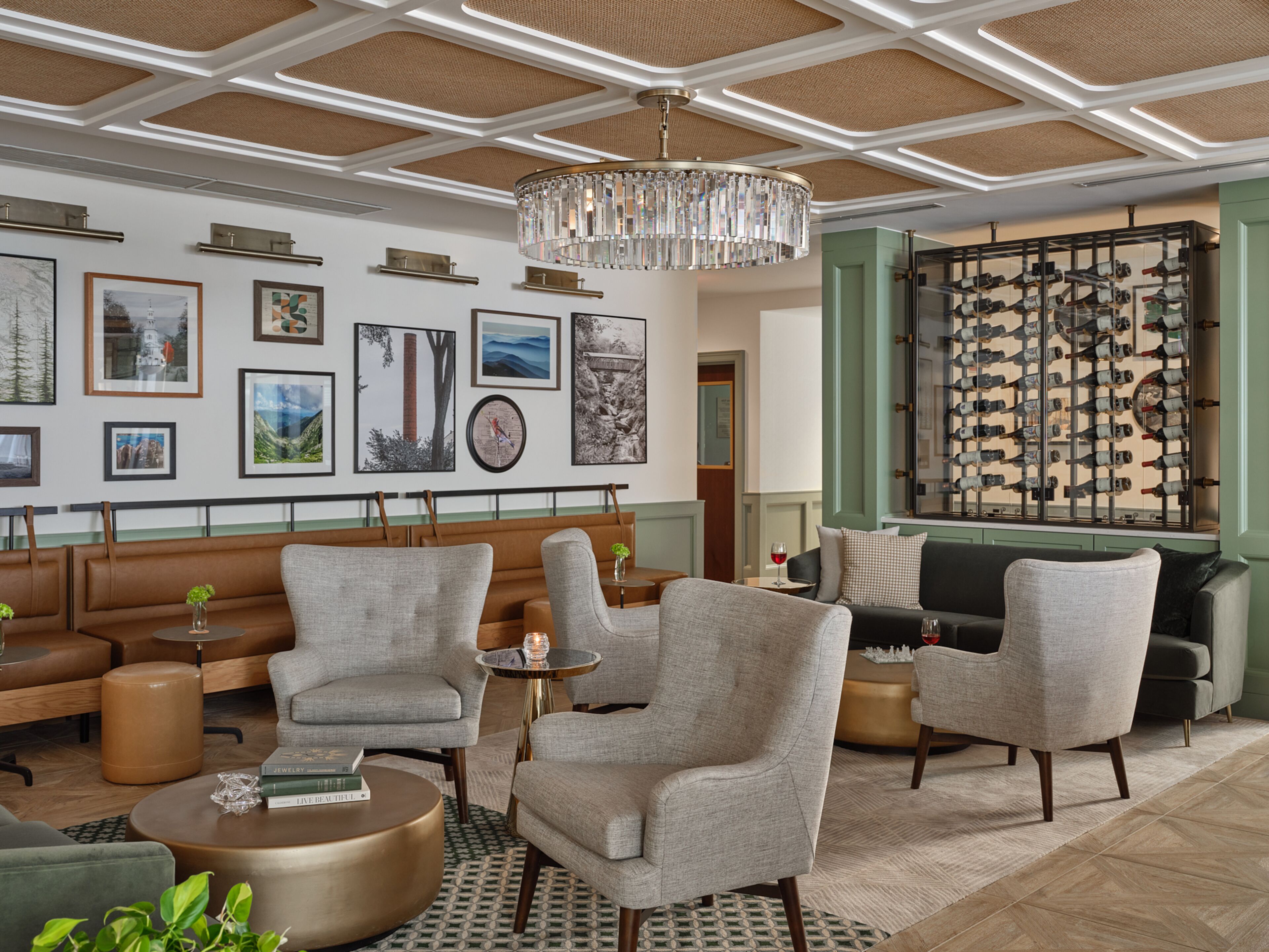A spacious lounge with a high ceiling, a chandelier, and a wall of framed artwork.