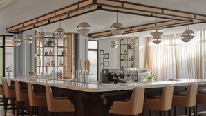 A modern bar area with a central island, bar stools, pendant lighting, and a wine rack. - Six South St Hotel (Hanover)