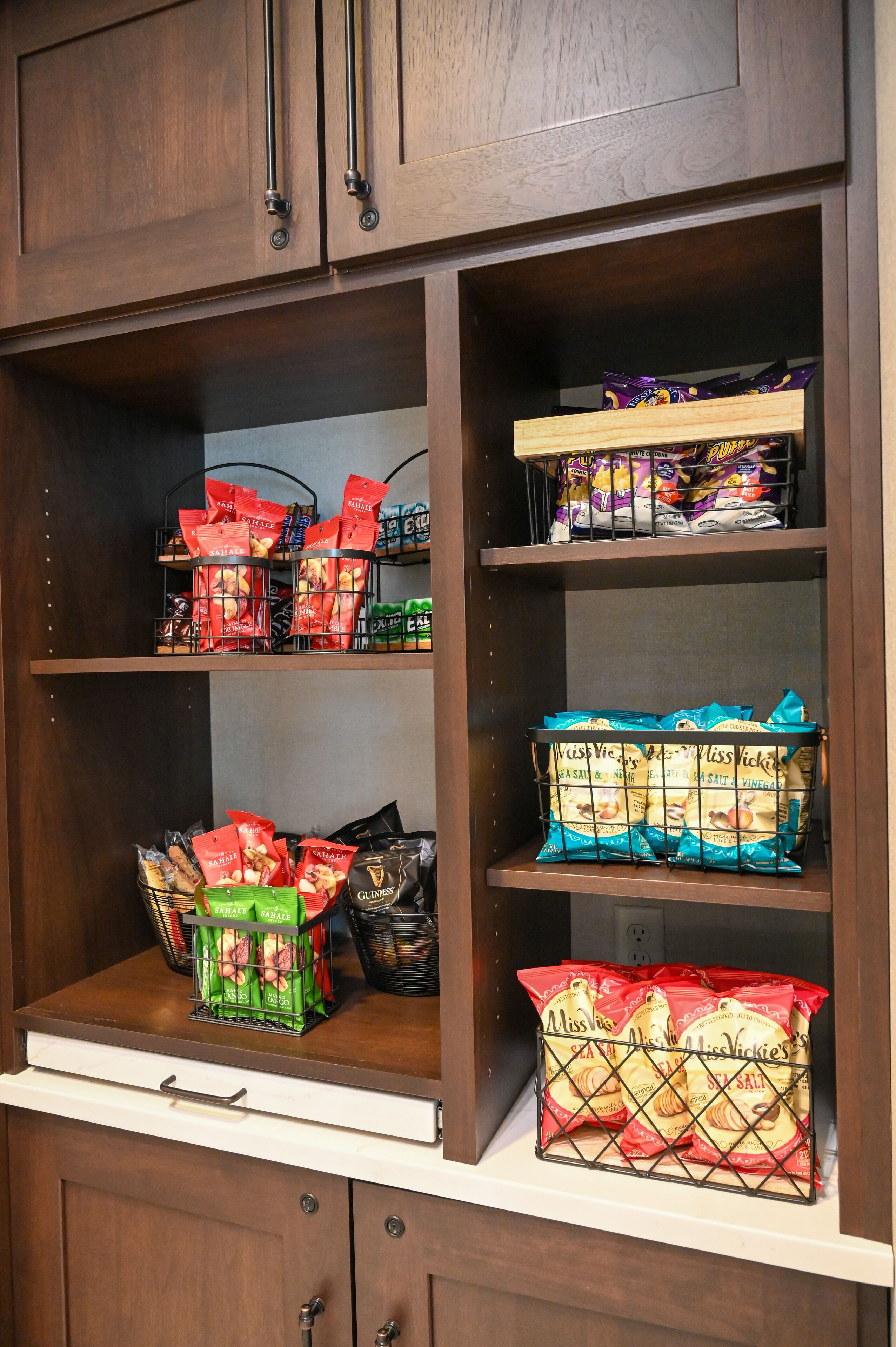 A pantry with shelves stocked with various food items, including snacks and condiments.