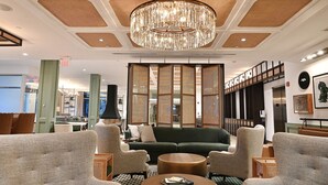 A lobby with a chandelier, sofas, and a coffee table. - Six South St Hotel (Hanover)