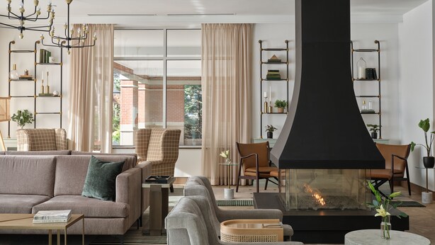 A modern living room with a fireplace, sofas, and a dining area. - Six South St Hotel (Hanover)
