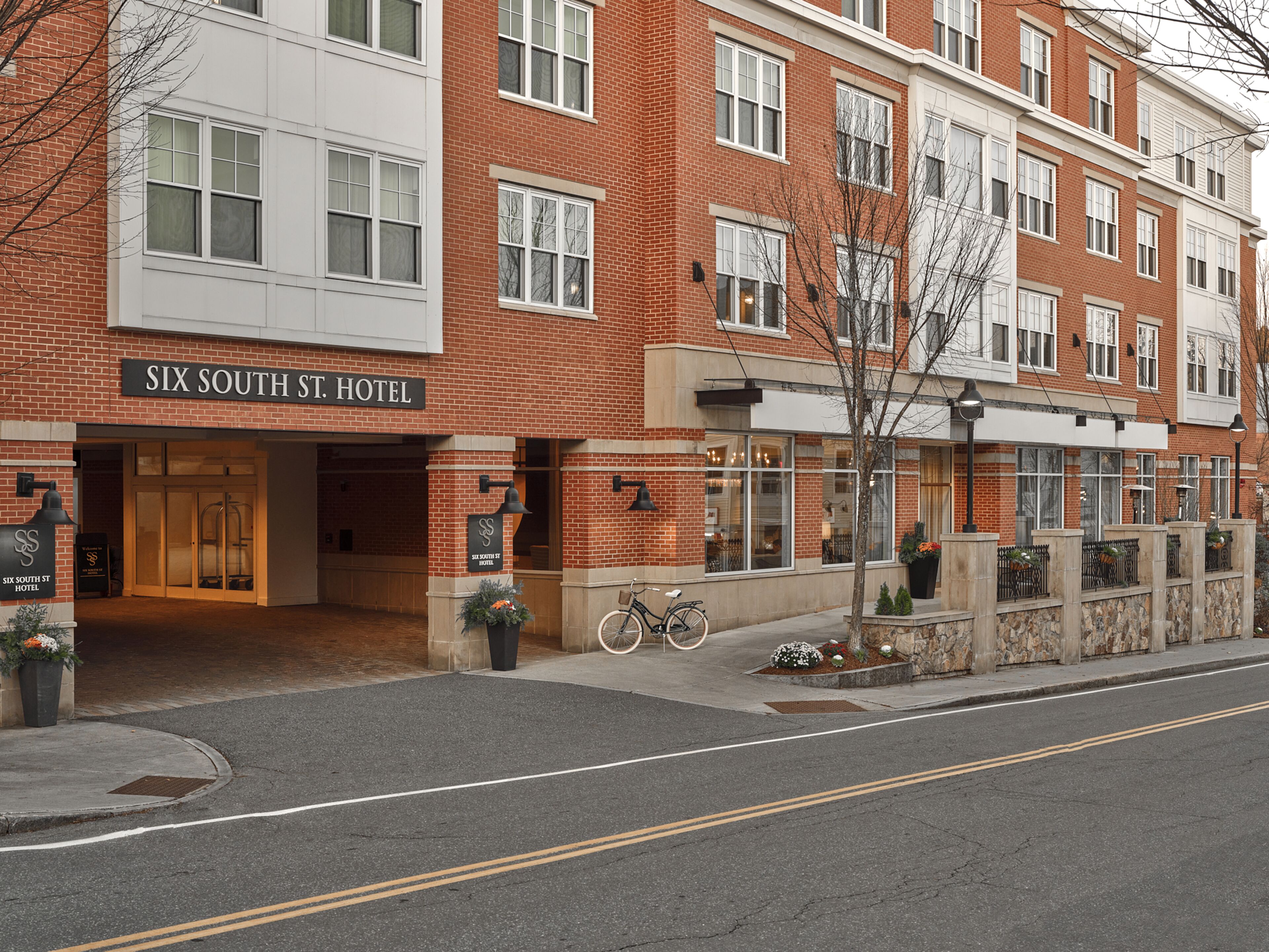A multi-story brick building with a sign reading "Six South St. Hotel".