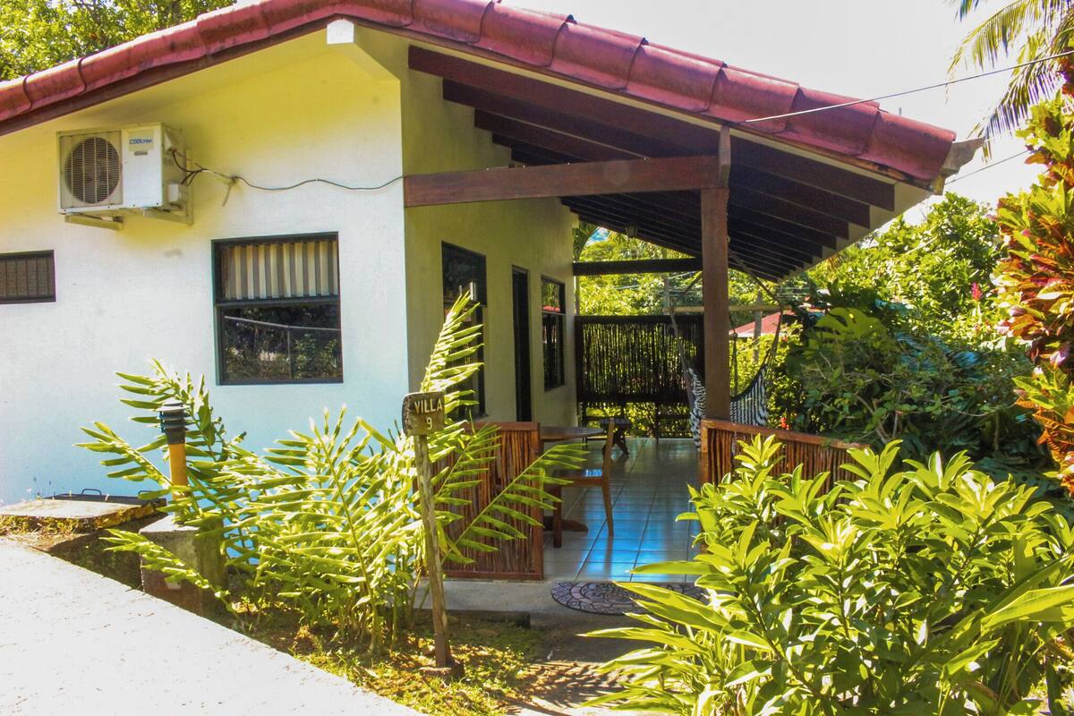 A house with a covered porch, a small staircase, and a sign indicating 'Villa 9'.