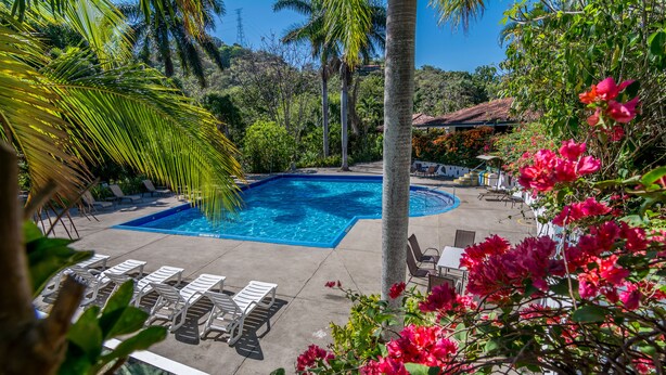 A pool area with lounge chairs and a view of the surrounding greenery.