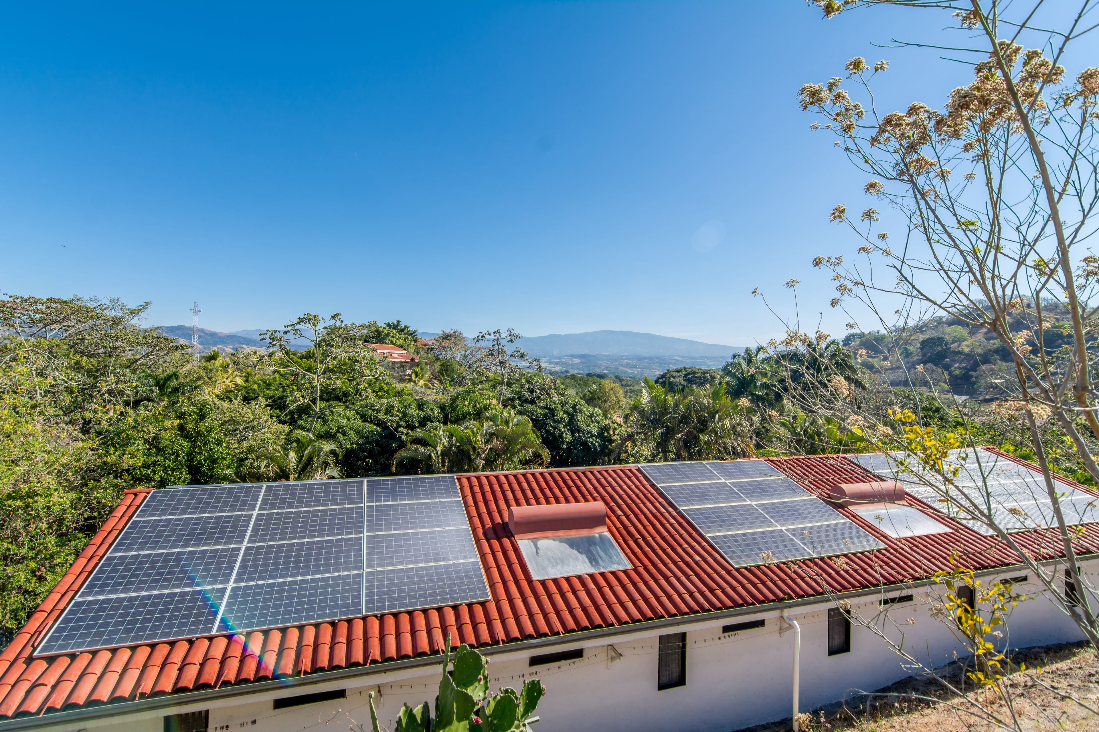 Un bâtiment doté d’un toit recouvert de tuiles rouges et de panneaux solaires.
