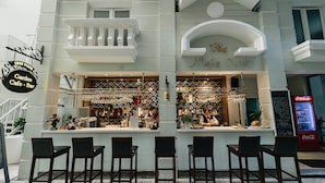 A bar with a counter and bar stools, a Coca-Cola vending machine, and a sign reading "Garden Cafe - Bar". - Eden Plaza Danang (Da Nang)