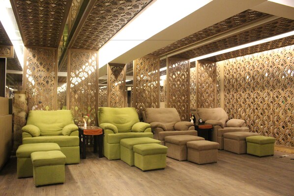 Una habitación con varios sofás y otomanas verde y beige dispuestos alrededor de una mesa central.