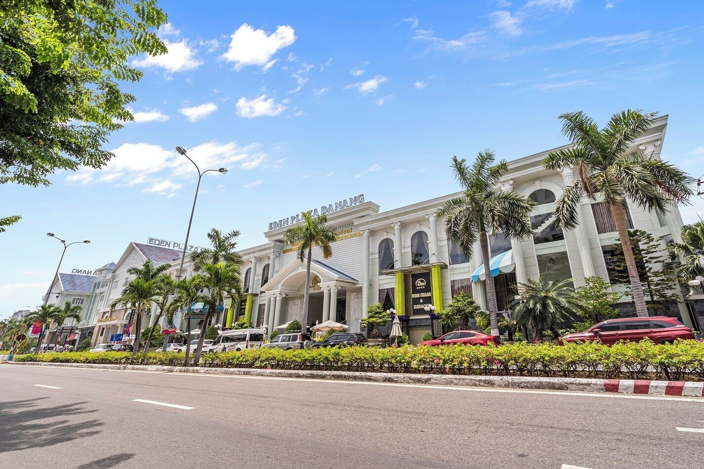 A hotel with a prominent entrance, palm trees, and a clear blue sky.