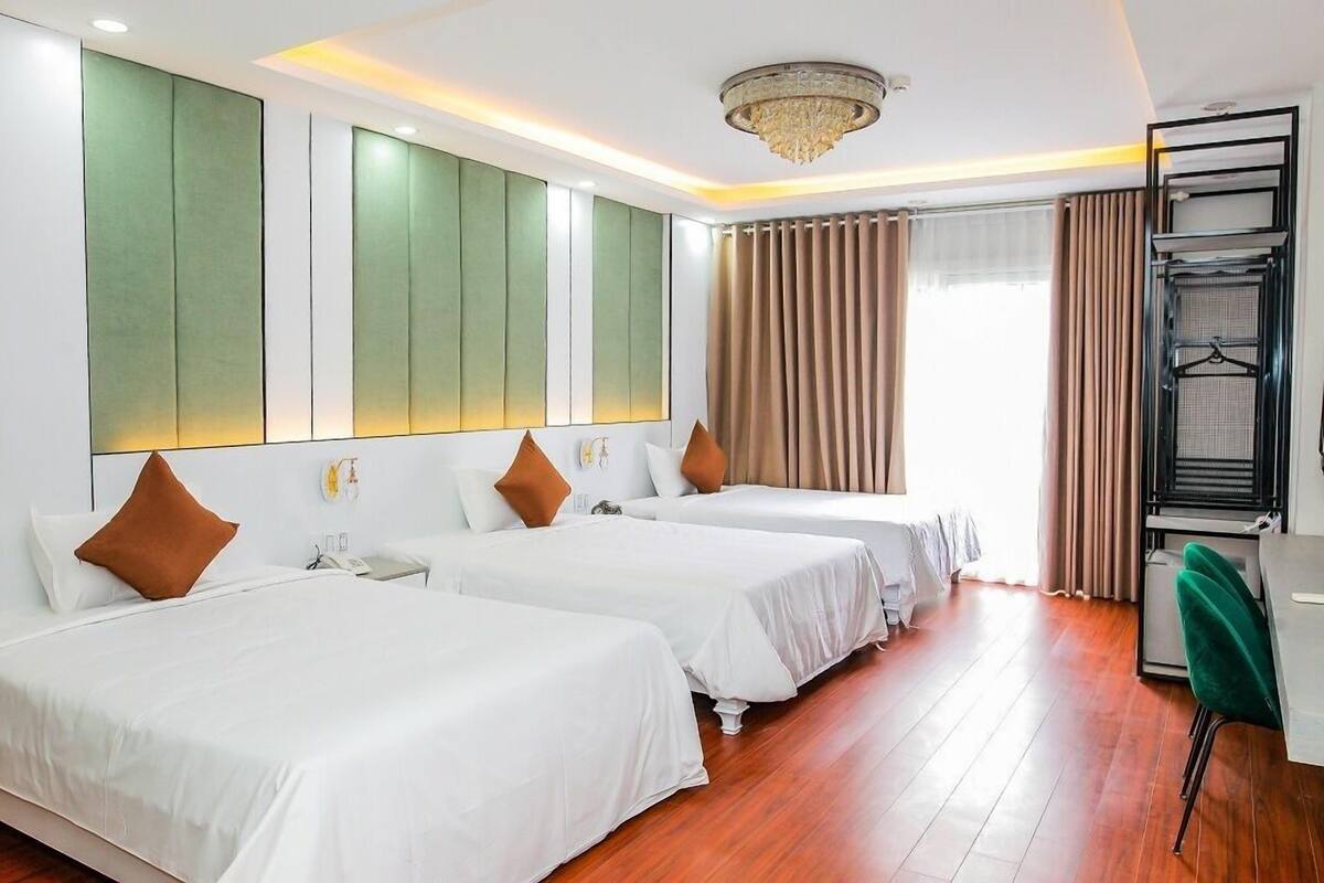 A hotel room with two beds, a desk, and a hanging chair.