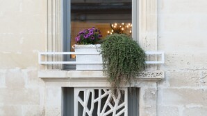 Une fenêtre avec un balcon blanc, un pot de fleurs et un cadre de fenêtre décoratif.