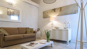 Un salon avec un canapé marron, une table basse blanche, une lampe et une petite table d’appoint blanche sur laquelle se trouve un bol.