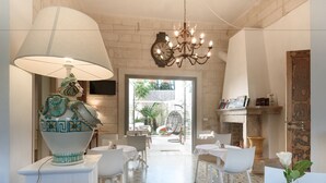 Un coin repas avec des meubles blancs, un lustre et un vase décoratif.
