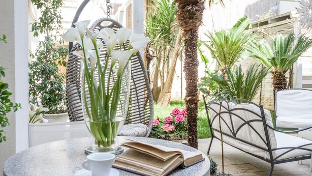 Une table ronde avec un livre, une tasse et un vase de fleurs.