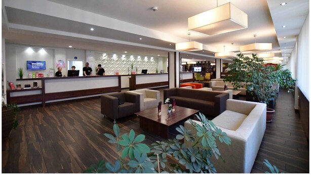 Eine moderne Lobby mit Empfangstresen, Sitzbereich und Bar.