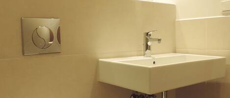 Une salle de bain équipée de toilettes, d’un lavabo et d’un porte-serviettes avec des serviettes pliées.