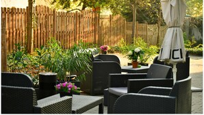 Ein Patio mit Korbmöbeln, Blumentöpfen und einem Holzzaun.