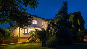 A two-story house with a well-maintained lawn and a large tree in the front yard. - Wein & Landhaus Willi Opitz (Illmitz)