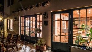 A warmly lit building with large windows and doors, wooden furniture, and potted plants. - Wein & Landhaus Willi Opitz (Illmitz)
