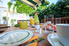 A table set for breakfast with plates, cups, and a glass of orange juice. - Wein & Landhaus Willi Opitz (Illmitz)