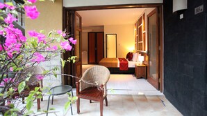A hotel room with a bed, a nightstand, and a chair. There is a door leading to another room. - Sanur Seaview Hotel (Denpasar)