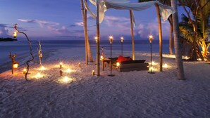 A beach setting with a canopy, candles, and a bench.
