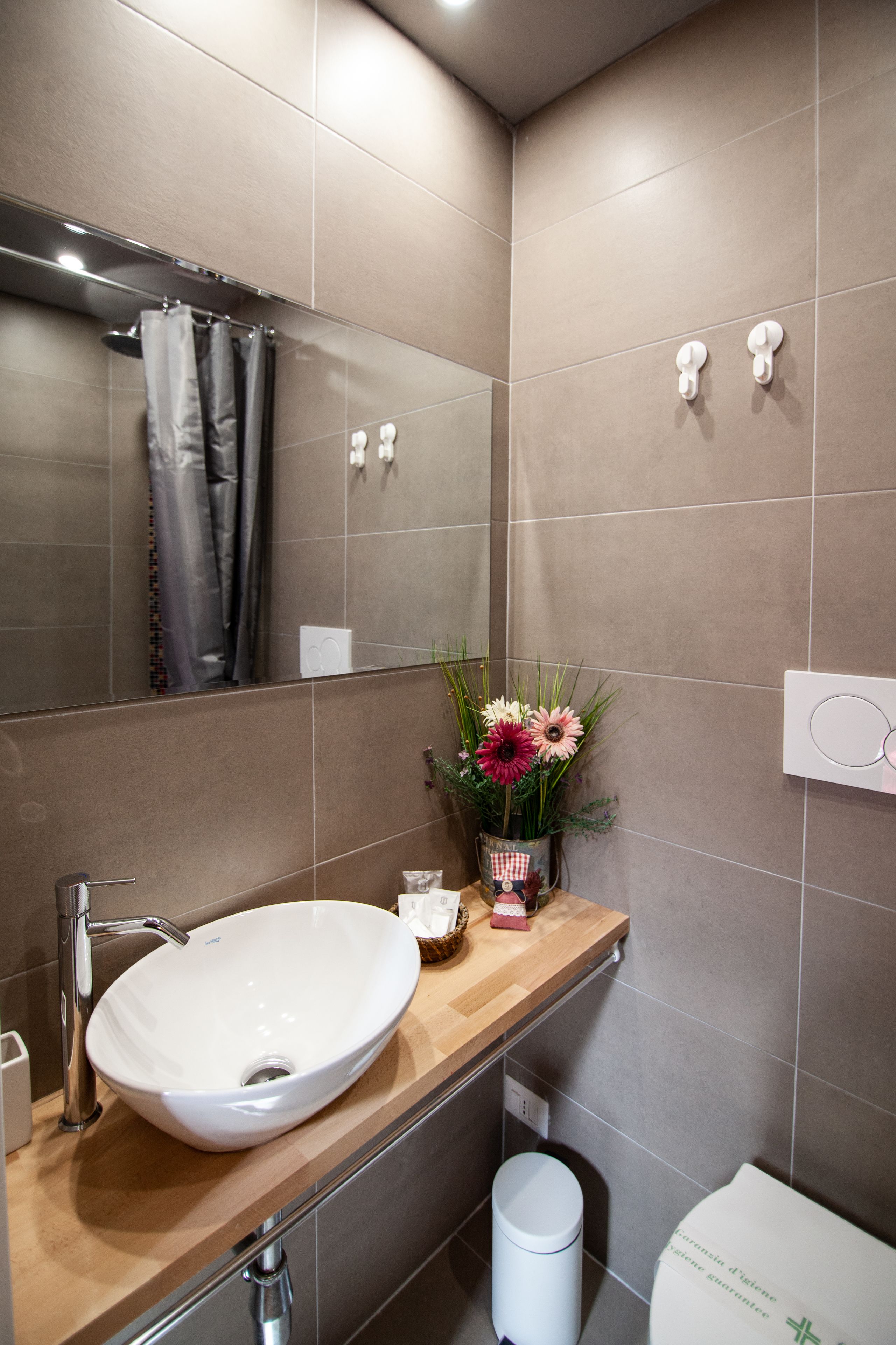 A modern bathroom with a large mirror, a white sink, and a toilet.