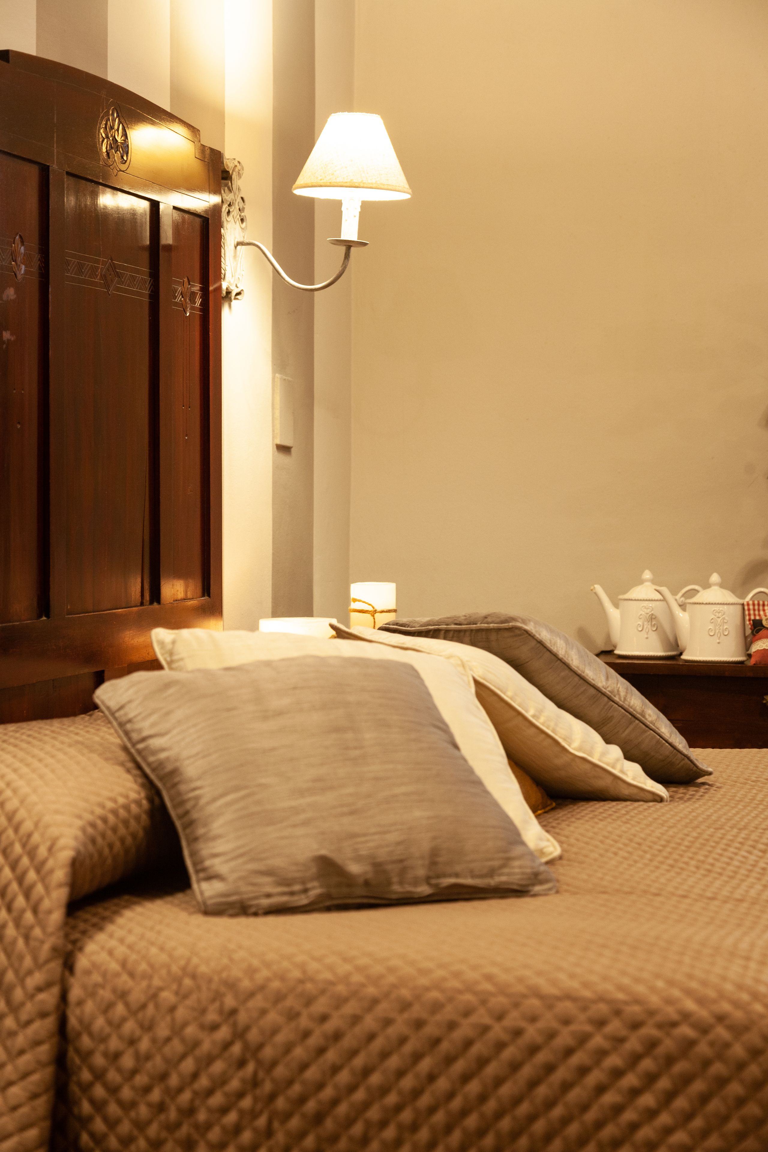 Una habitación de hotel con cama, almohadas, una mesita de noche, una lámpara y un armario de madera.