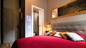 A hotel room with a large bed, a headboard, a mirror, and a nightstand with a lamp. - La Colonna ( Historic Center ) (Lucca)