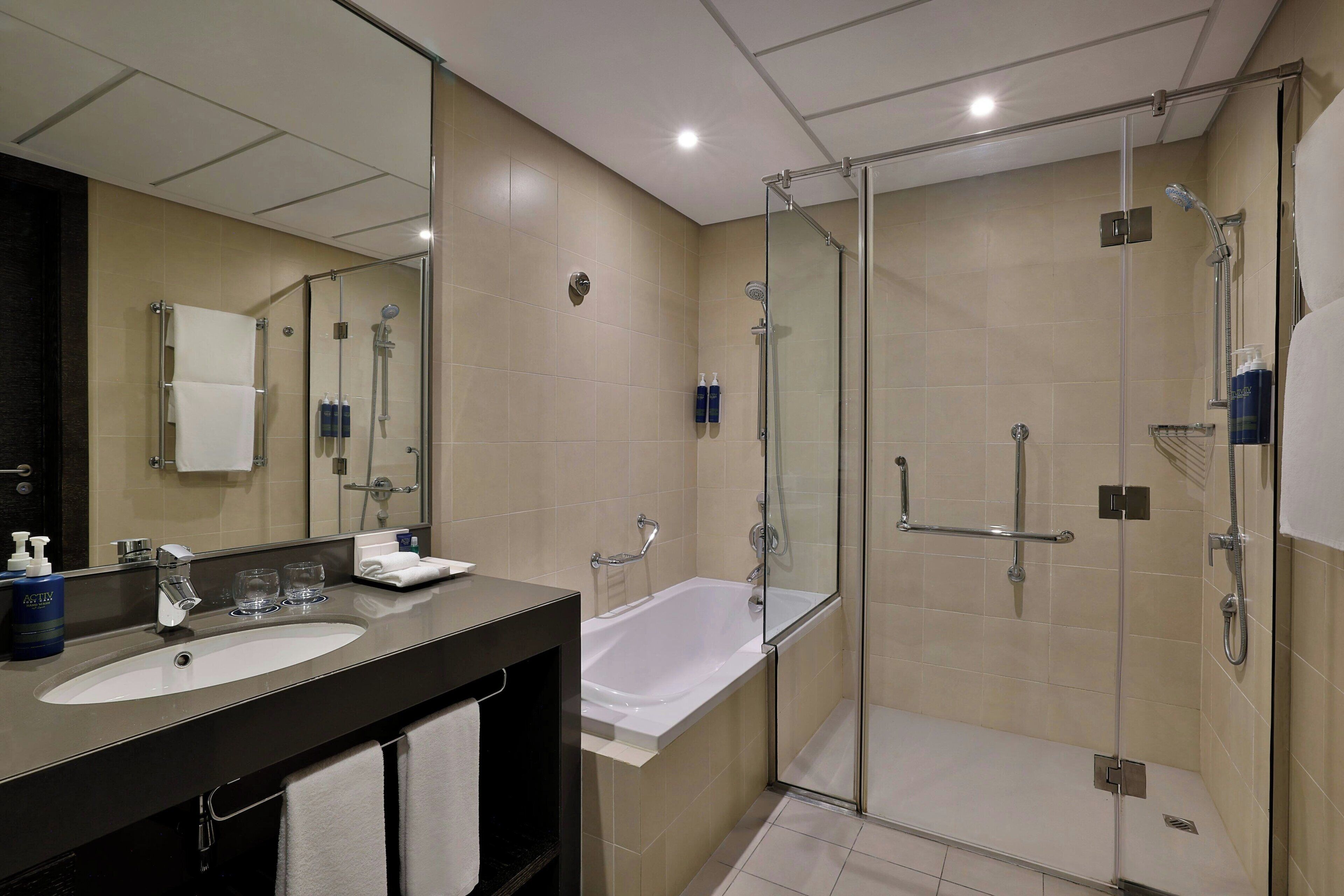 A modern bathroom with two sinks, a bathtub, and a glass-enclosed shower area.