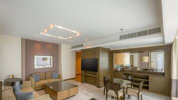 A modern hotel room with a living area, a dining table, and a TV.