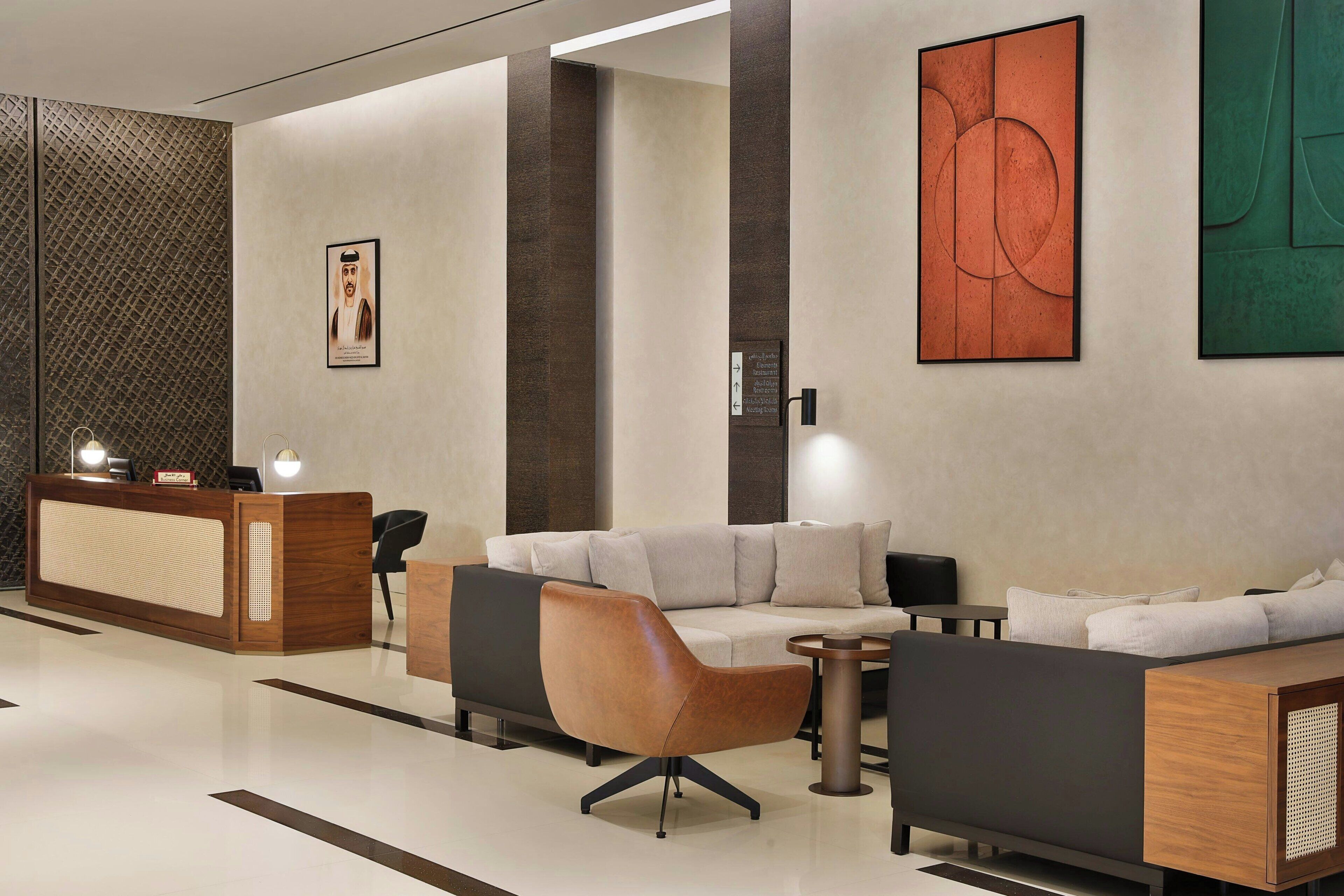 A modern lobby with a reception desk, seating area, and artwork on the walls.