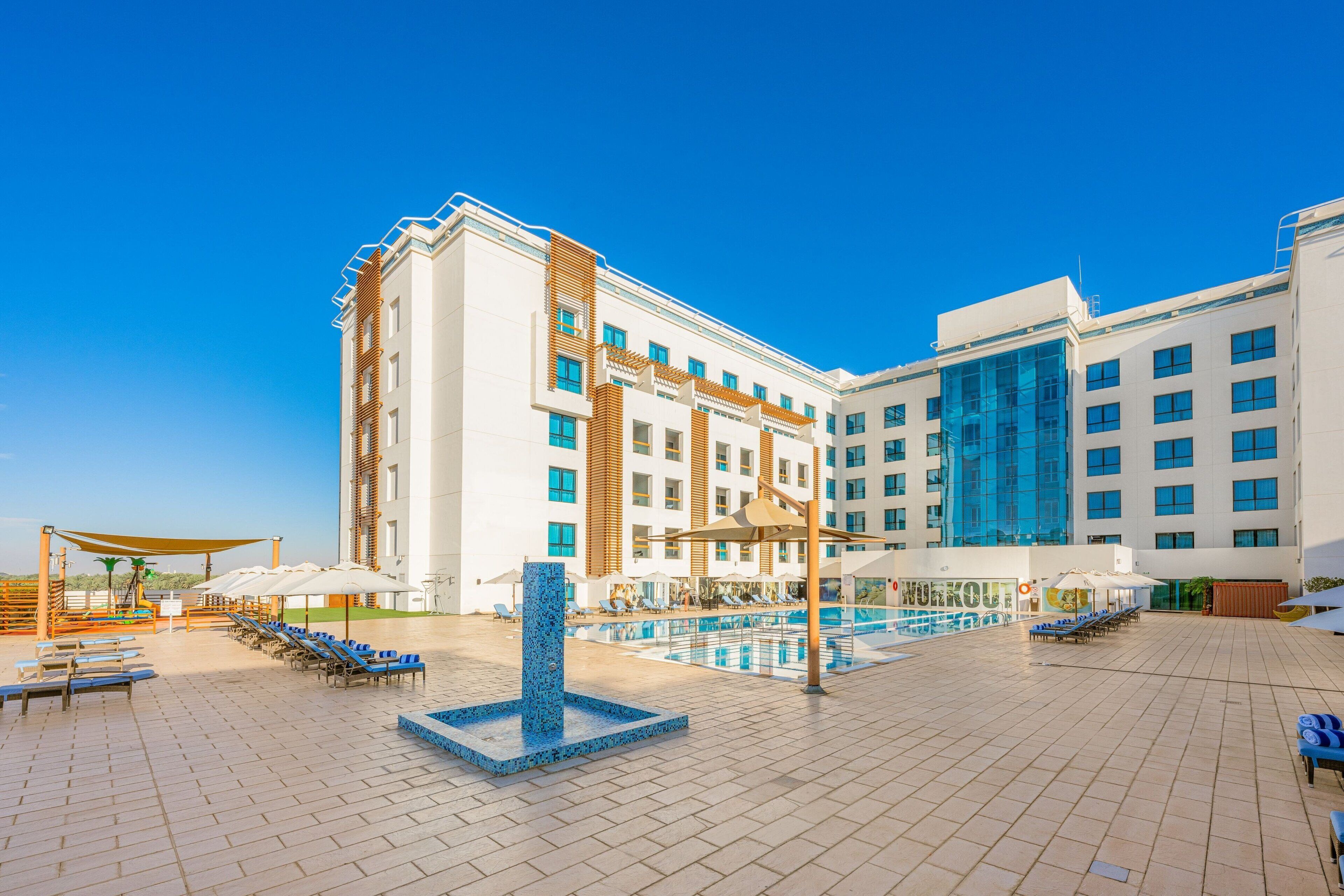 Un hotel con piscina, sillones de descanso y sombrillas.