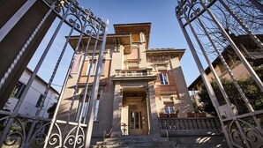 A building with a grand entrance, a staircase leading up to the door, and wrought iron gates. - Villa Tower Inn (Pisa)
