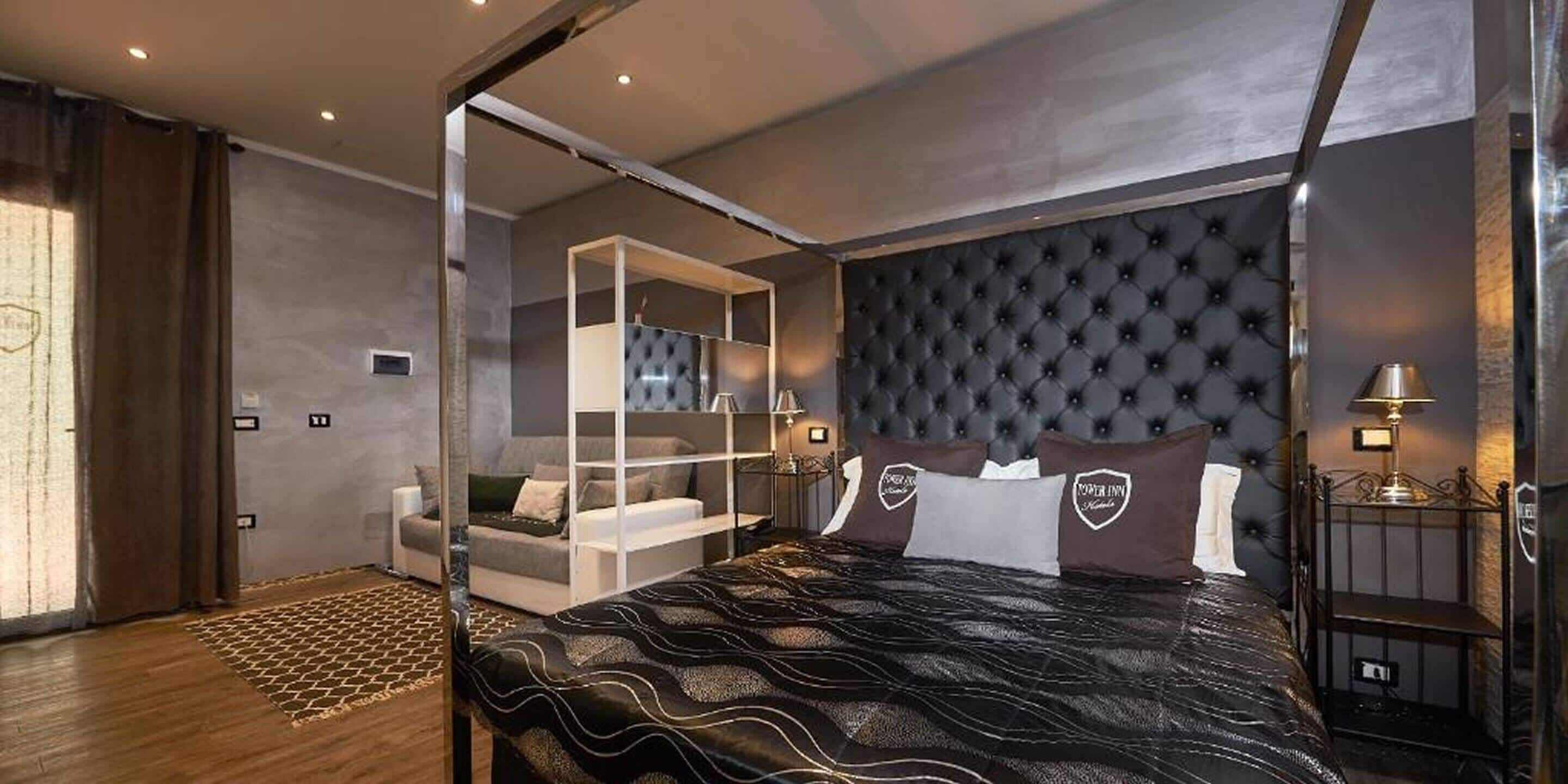 Ein modernes Schlafzimmer mit einer gesteppten Kopfteil, einem Bett mit einem gemusterten Bettbezug, einer Sitzecke mit Sofa und Couchtisch sowie einer Glastrennwand.