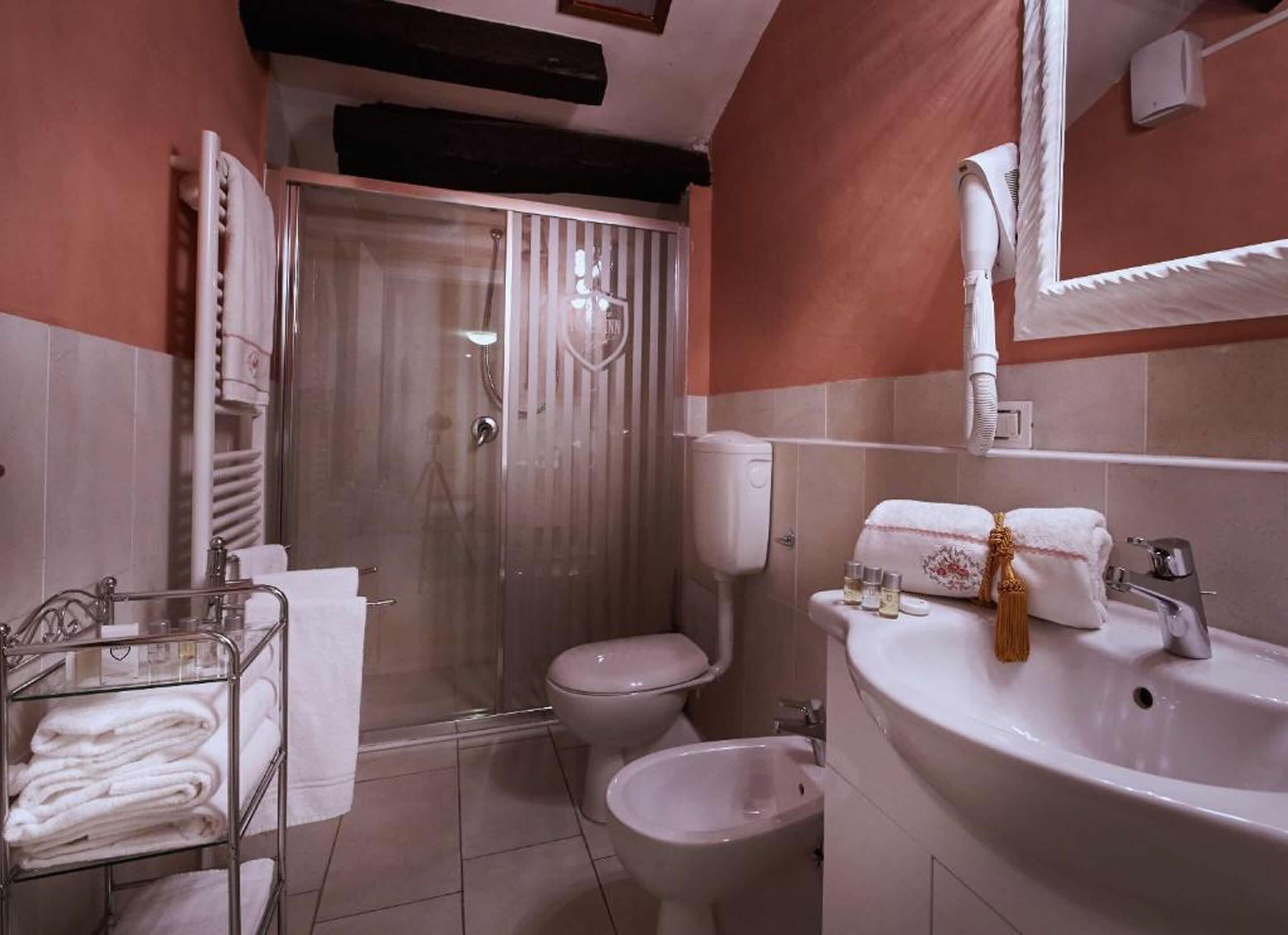 A bathroom with a glass-enclosed shower, a toilet, a bidet, and a sink with a mirror.