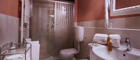 A bathroom with a glass-enclosed shower, a toilet, a bidet, and a sink with a mirror.