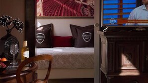 A hotel room with a bed, a television, a dining area with a table and chairs, and a wall with a theater mural. - Villa Tower Inn (Pisa)