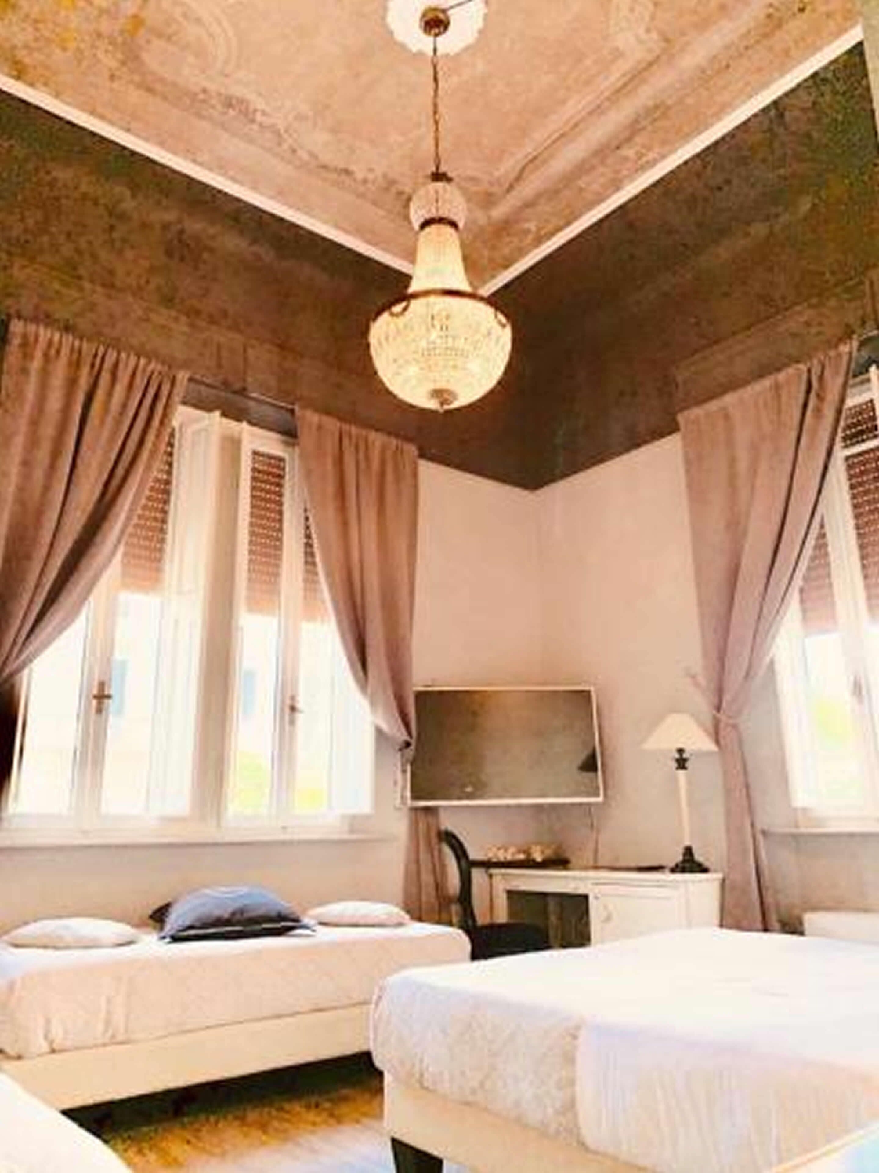 A bedroom with two beds, a ceiling fan, a TV, and a desk.