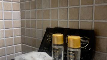 Un comptoir de salle de bain avec des articles de toilette, notamment un flacon de shampoing, un flacon d’après-shampoing et un paquet de disques de coton, le tout portant la marque « Tower Inn Hotels ».