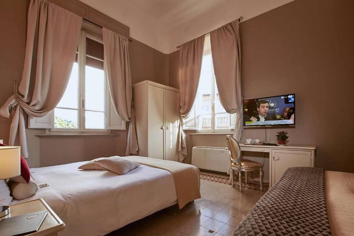 Una habitación de hotel con cama, escritorio, televisor y sofá.