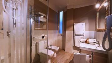 A modern bathroom with a glass shower enclosure, a toilet, bidet, and a sink with a towel rack.