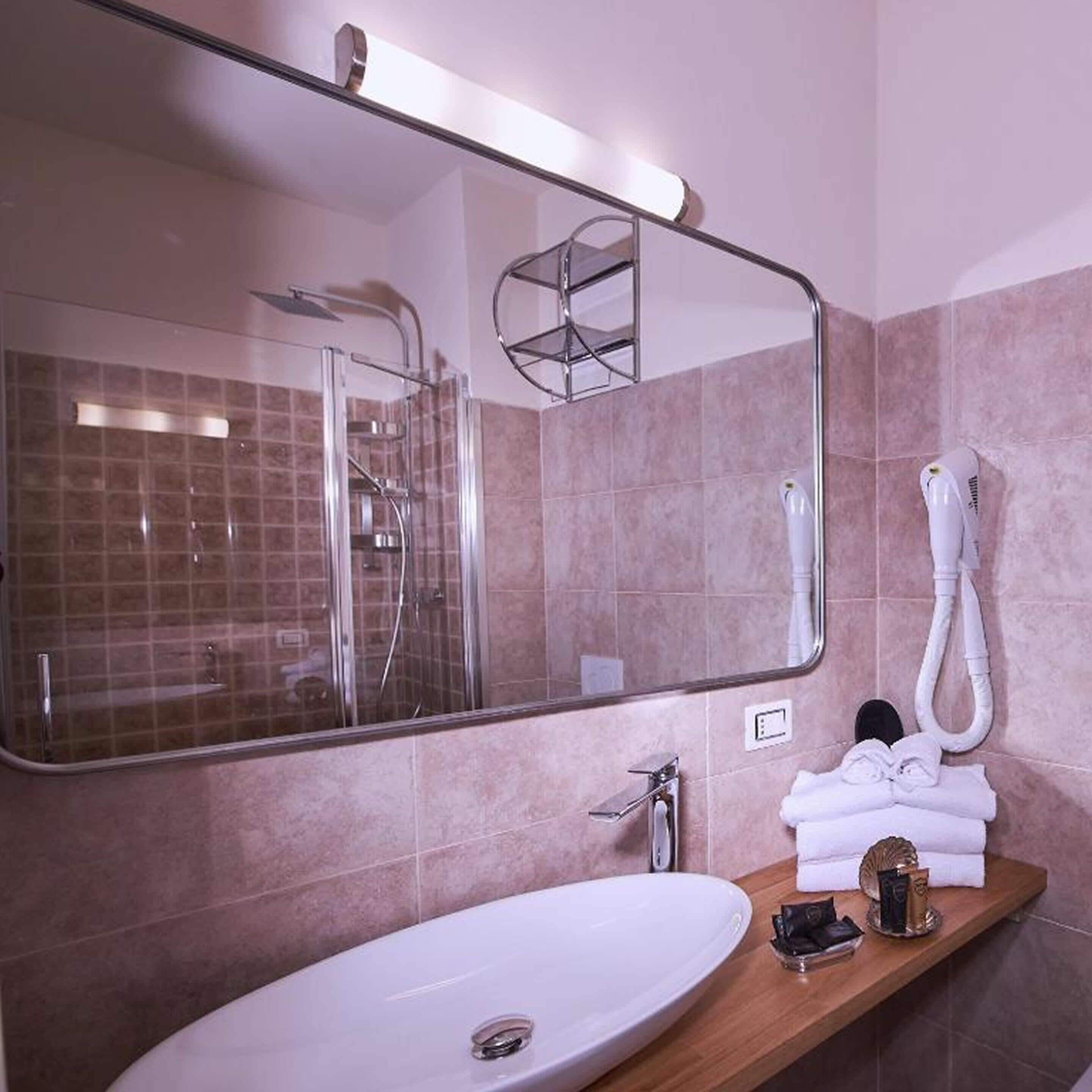 A modern bathroom with a large mirror, a shower enclosure, a sink, and a towel rack.