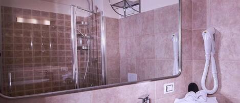 A modern bathroom with a large mirror, a shower enclosure, a sink, and a towel rack.