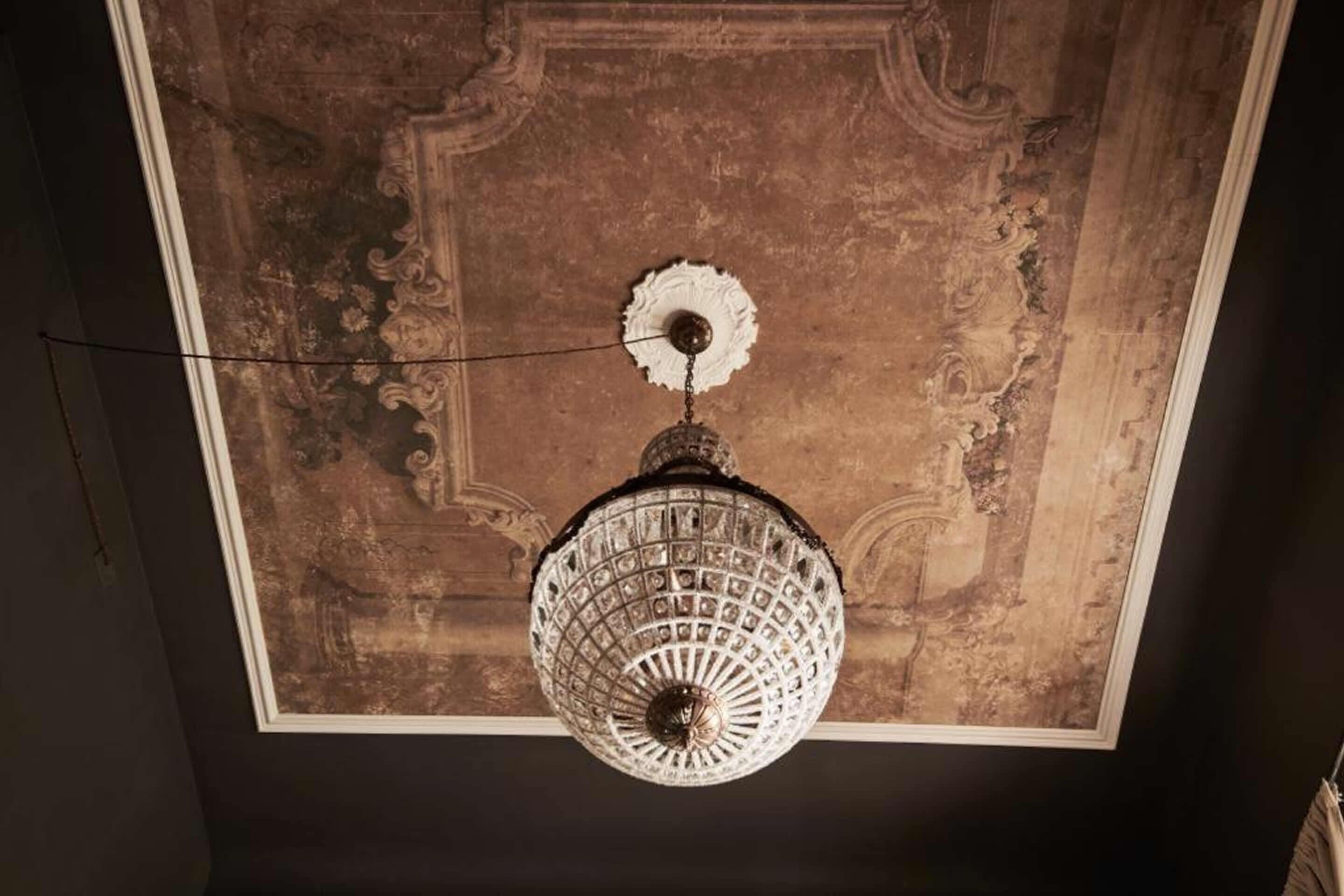 Un candelabro de diseño intrincado colgado del techo, decorado con yesería ornamentada.
