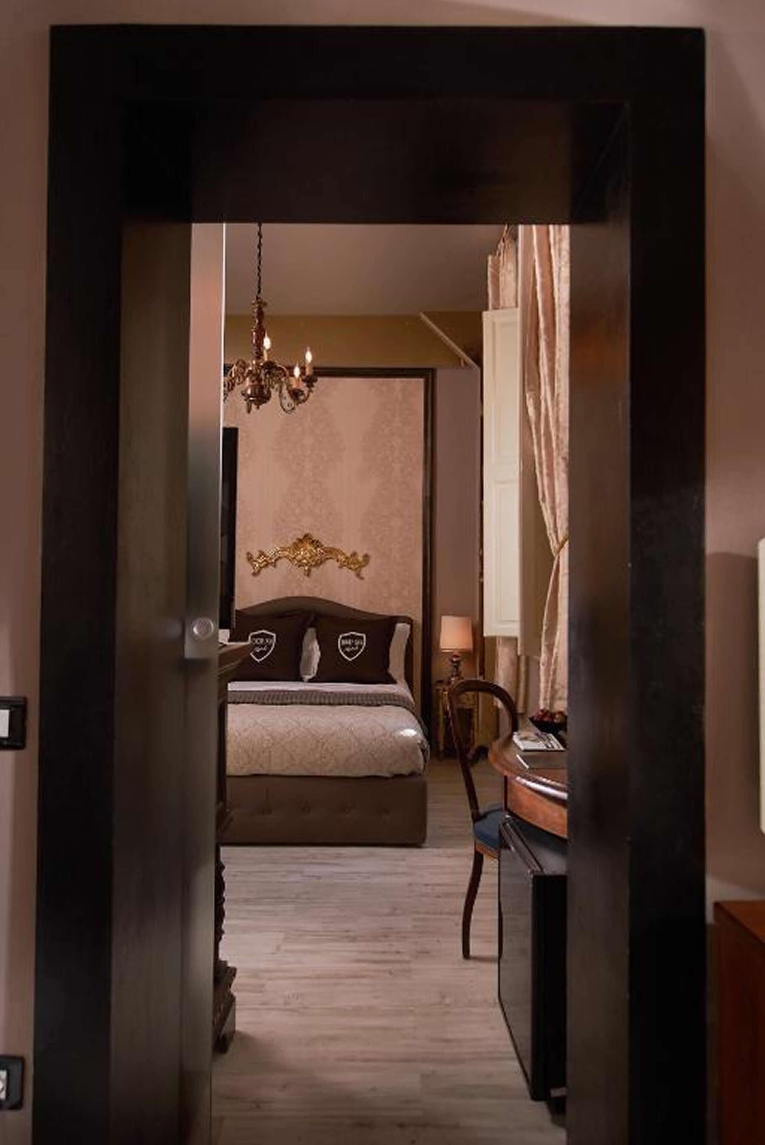 Een slaapkamer met een bed, een kroonluchter, een bureau en een stoel.