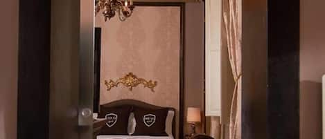 Een slaapkamer met een bed, een kroonluchter, een bureau en een stoel.