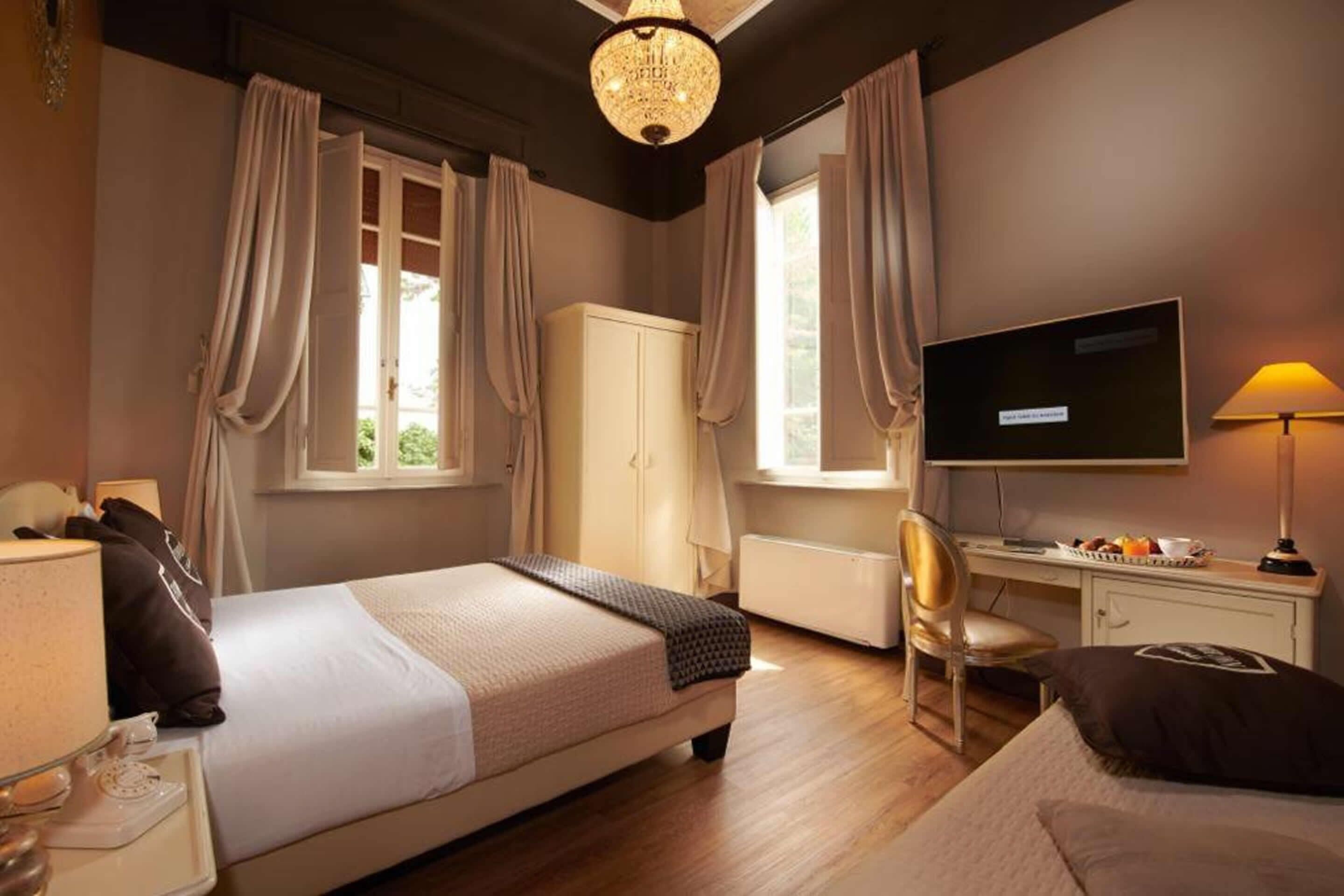 Una habitación de hotel con cama, escritorio, computadora, televisor y una silla.