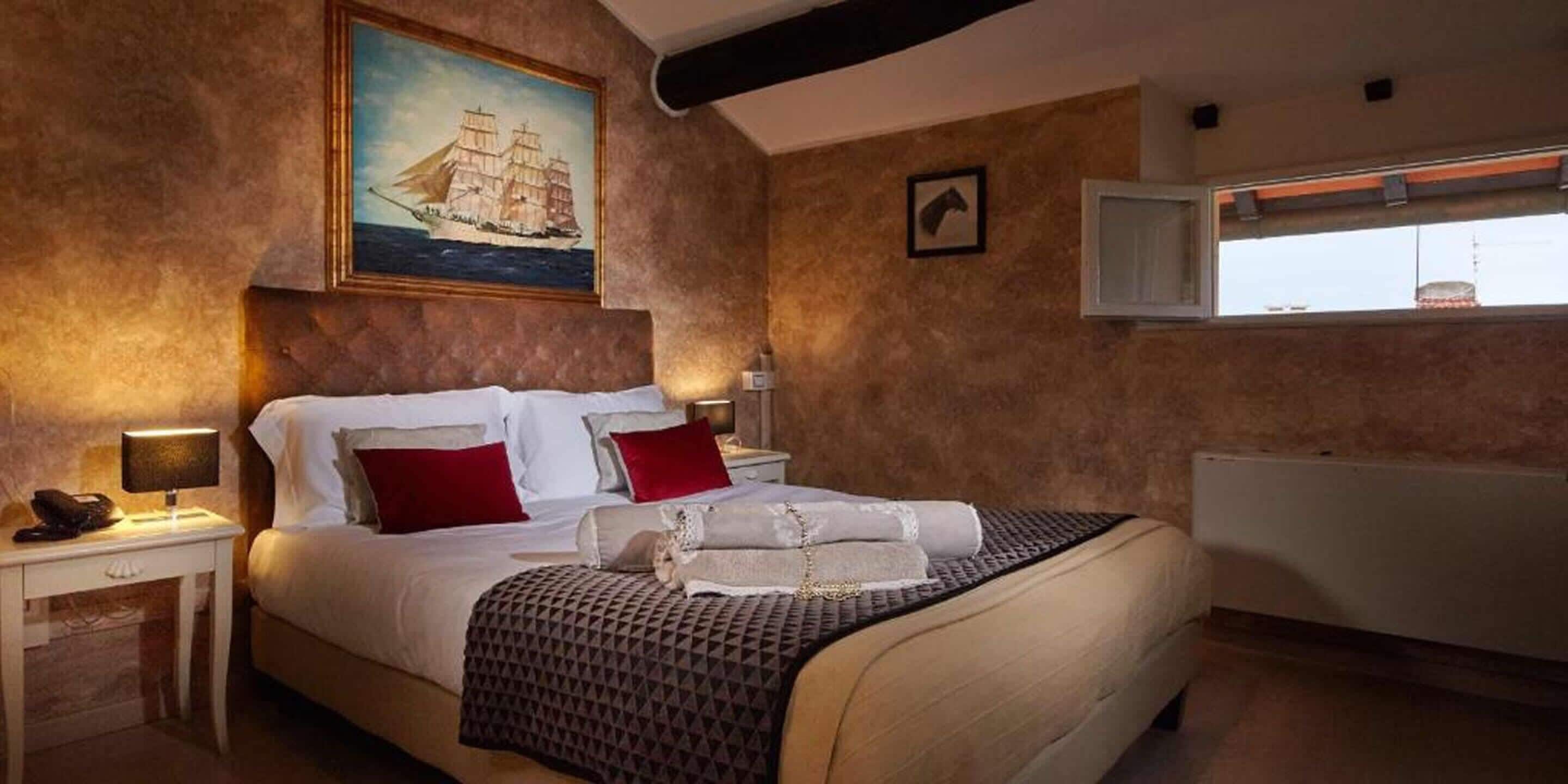 Un dormitorio con una cama grande, un cuadro de un barco, una ventana con persianas y una bañera blanca.